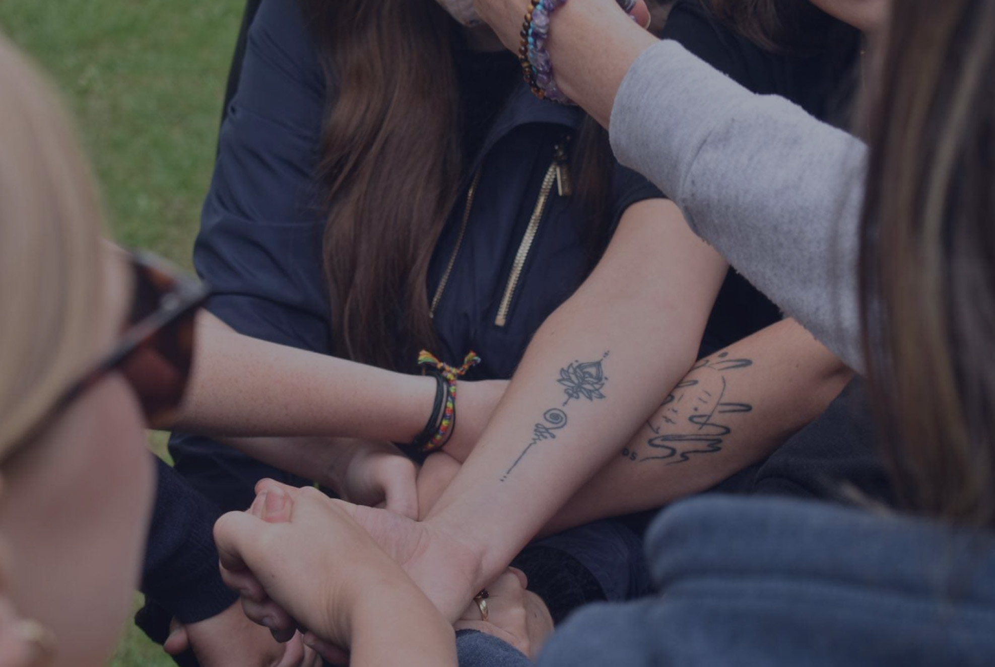 Two arms linked together with wrist tattoos, symbolizing solidarity