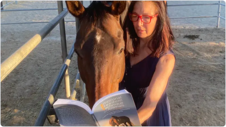 Joan Ranquet showing a horse the Emotional Freedom Technique book